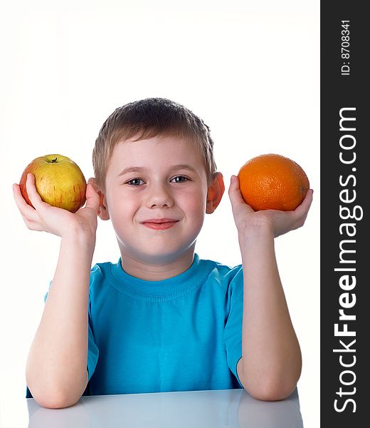 The child sits on a table with fruit. The child sits on a table with fruit