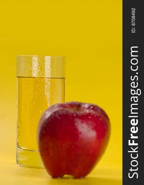 The big red apple and glass of apple juice on a yellow background. The big red apple and glass of apple juice on a yellow background