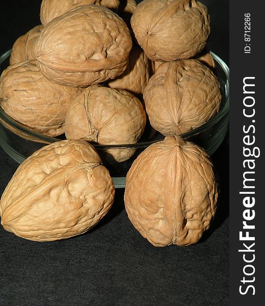 Walnuts in glass plate on black background