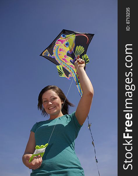 A teen smiles while holding a colorful kite on a windy spring day. A teen smiles while holding a colorful kite on a windy spring day.