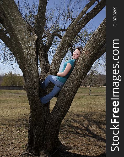 A teenage girl kicks back in a tree. A teenage girl kicks back in a tree.