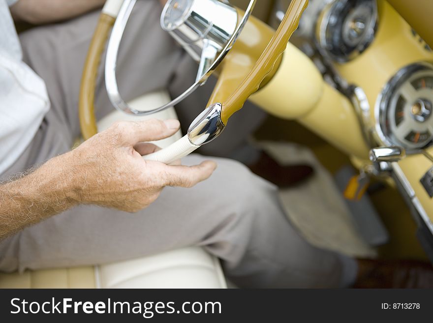 Older driver steering vintage yellow with view of dashboard. Older driver steering vintage yellow with view of dashboard