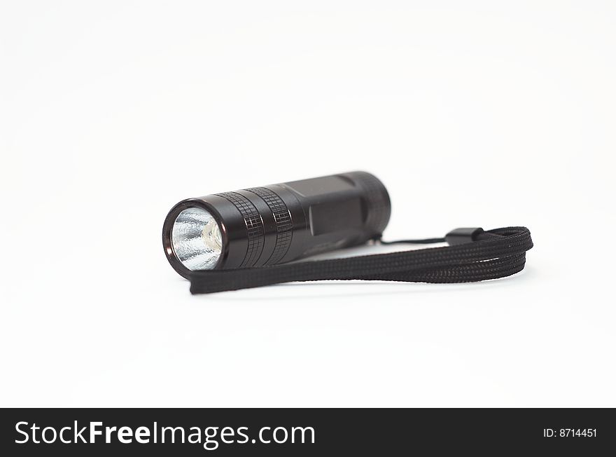 Black flashlight with hand strap laying on white. Black flashlight with hand strap laying on white