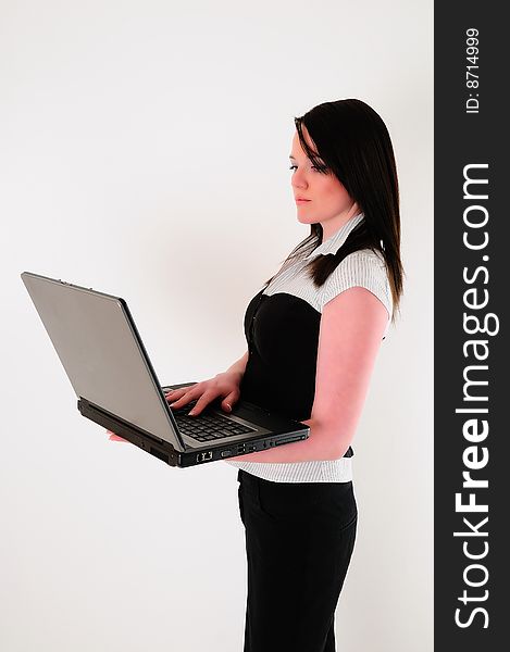 Female model holding a lptop wearing an office outfit looking like a casual business woman. Female model holding a lptop wearing an office outfit looking like a casual business woman
