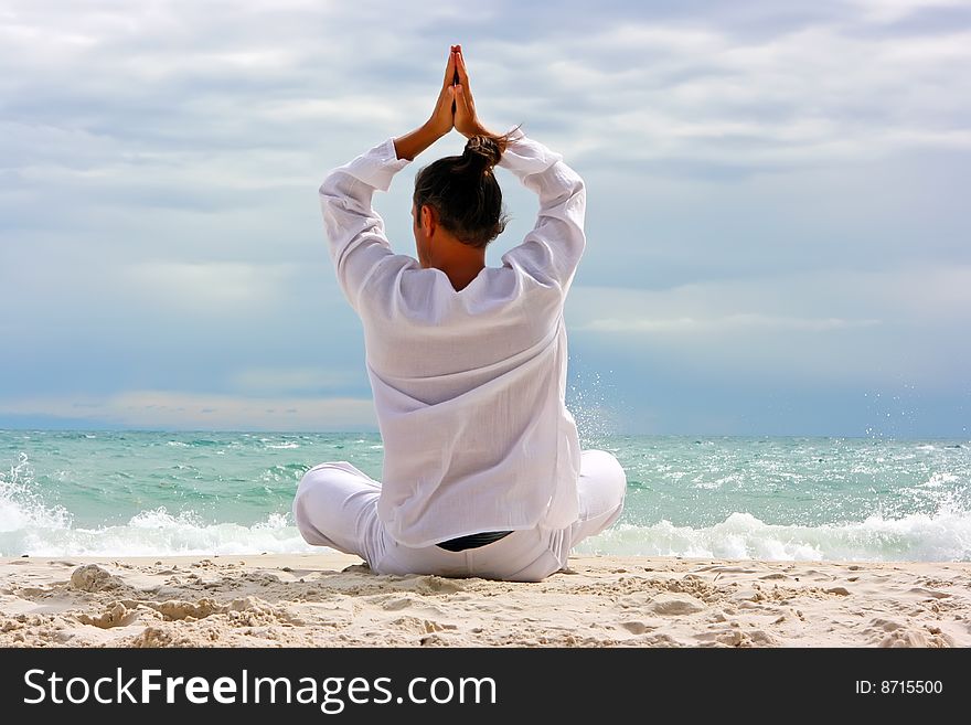 Young man practising yoga on the sandy beach. Young man practising yoga on the sandy beach