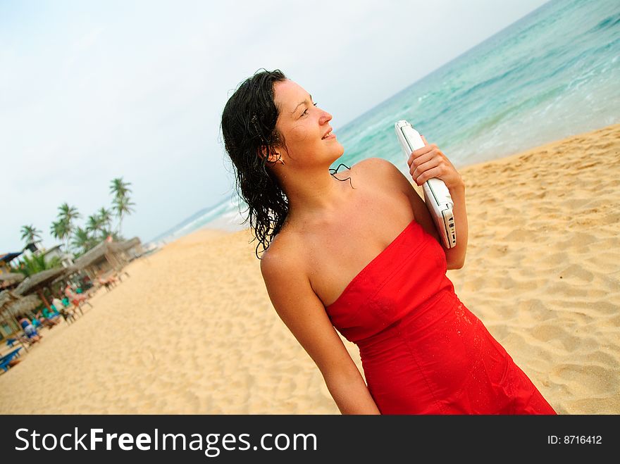Beautiful smiling young woman with laptop on beach