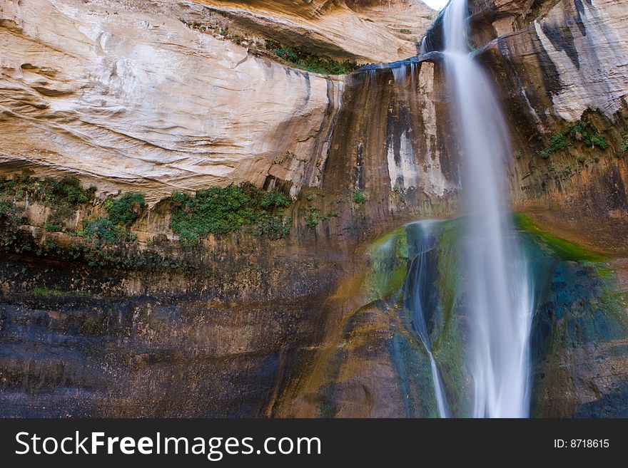 Waterfall against red rock in tree covering of Escalante, Utah
