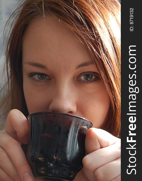 Young woman  drinking from a black cap. Young woman  drinking from a black cap