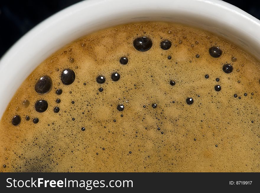 Closeup of a small white cup of freshly brewed coffee