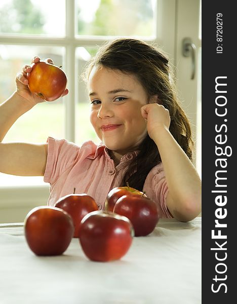 Brown haired child presenting an apple. Healthy lifstyle image.