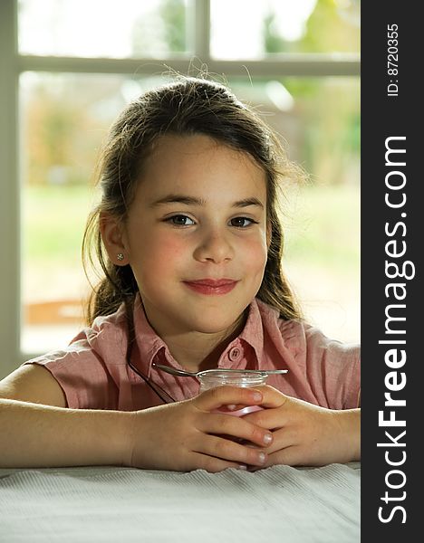 Brown haired child eating yogurt. Healthy lifstyle image.