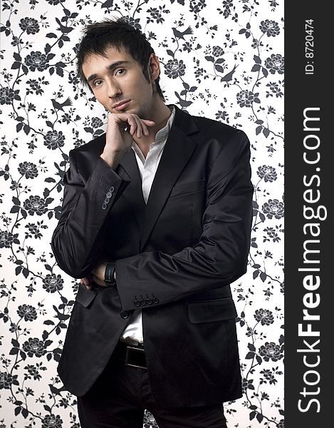 Young handsome man posing in black suit in front of a flower background. Young handsome man posing in black suit in front of a flower background