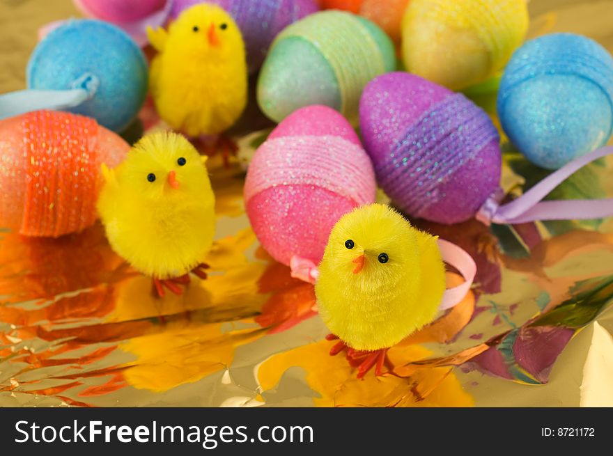 Close-up shot of Easter chicks with colorful eggs on golden background. Close-up shot of Easter chicks with colorful eggs on golden background