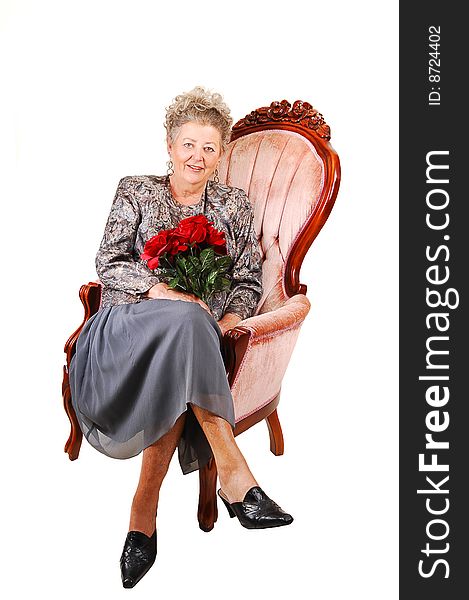 All dressed up elderly woman with red roses in her hand, for her 60th birdsday. Sitting in a pink armchair for white background. All dressed up elderly woman with red roses in her hand, for her 60th birdsday. Sitting in a pink armchair for white background.