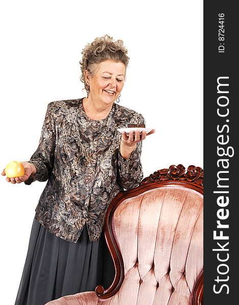 An elderly woman has to make a choice between an healthy apple or a sweet and delicious piece of chocolate cake. Over white background. An elderly woman has to make a choice between an healthy apple or a sweet and delicious piece of chocolate cake. Over white background.