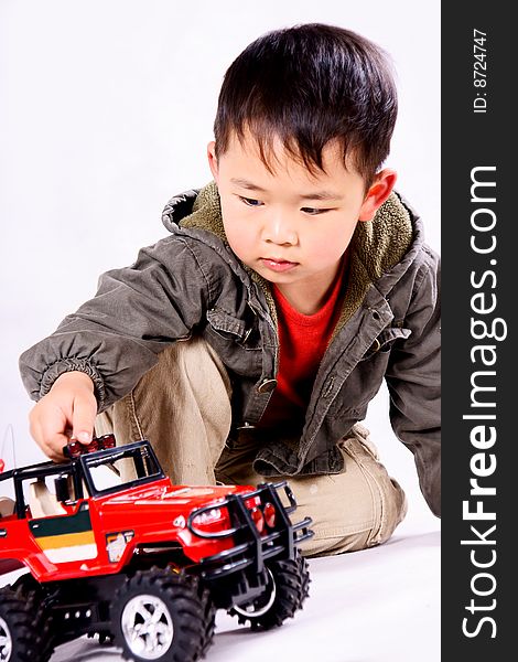 A picture of a little chinese boy looking attentively at a remote control car, smiling. A picture of a little chinese boy looking attentively at a remote control car, smiling