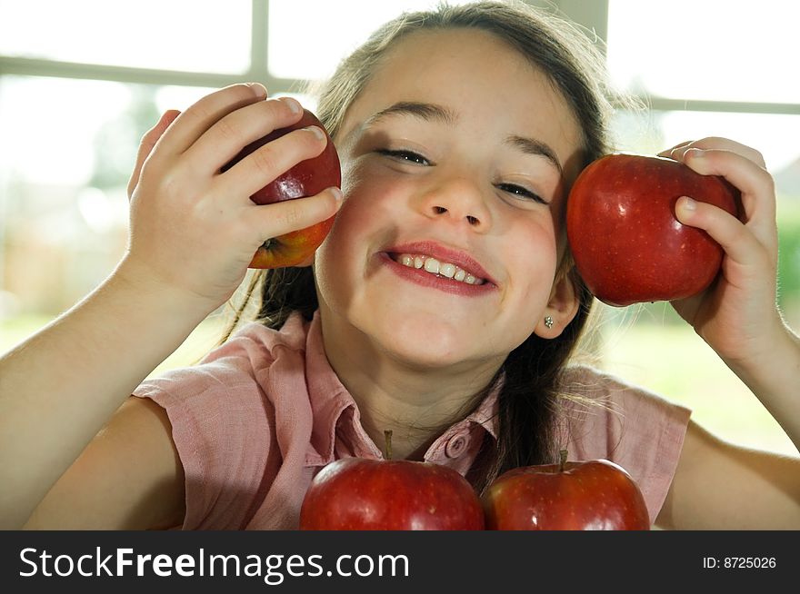 Brown haired child playing with apples. Healthy lifstyle image.