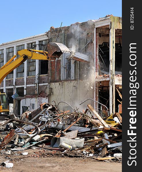 An excavator demolishing a two story concrete building. An excavator demolishing a two story concrete building