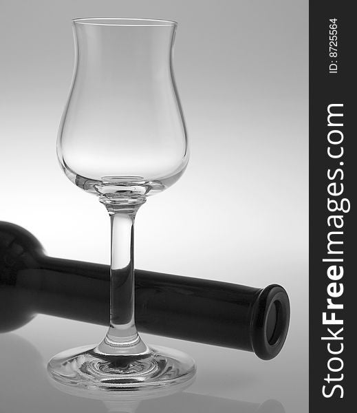 A liqueur glass with bottle on reflective background