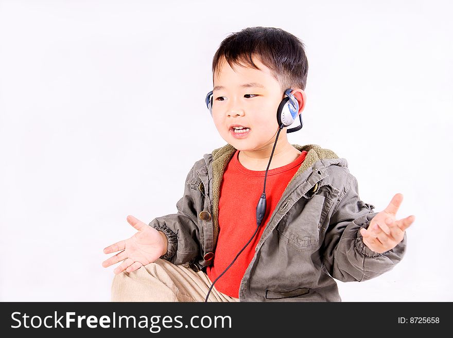 A picture of a little chinese boy listening to music with earphone, having great fun. A picture of a little chinese boy listening to music with earphone, having great fun