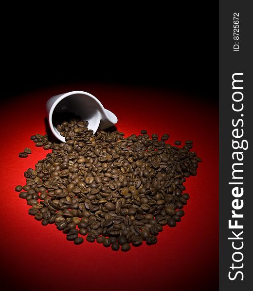 A fallen cup with coffee beans spread out.