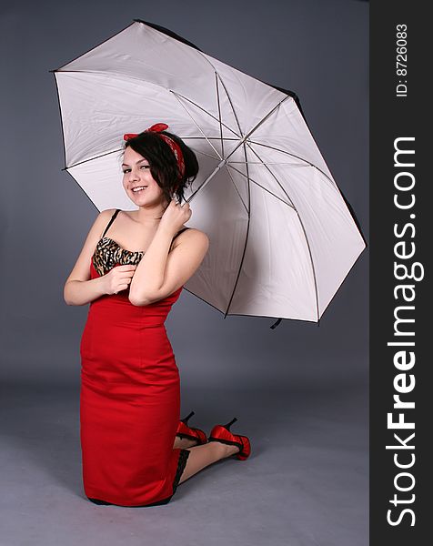 Laughing pinup girl sitting under umbrella in studio