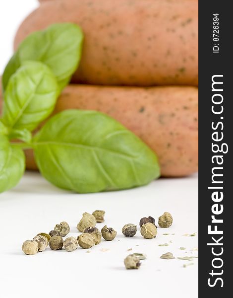 Detail of sausages with basil and green pepper on a white background