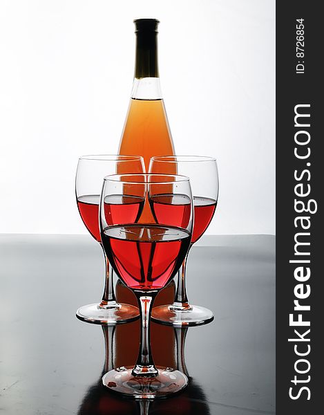 Bottle and glasses of wine on white background with reflections