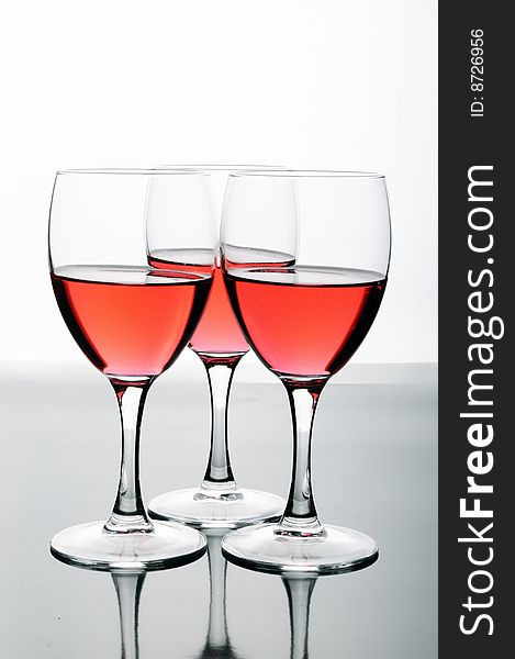 Bottle and glasses of wine on white background with reflections