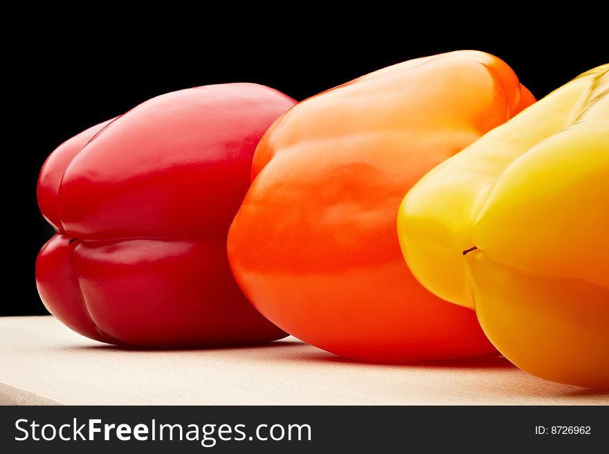 A red, yellow, and orange peppers on black background