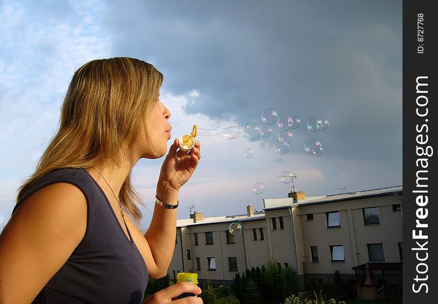A girl blowing bubbles to the sky. A girl blowing bubbles to the sky