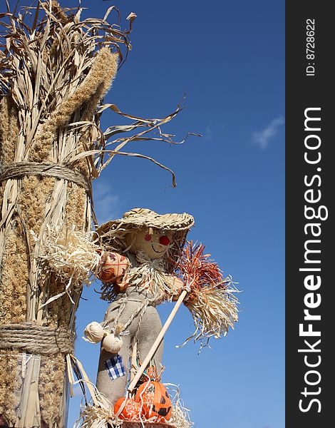 Sun is shining and the scarecrow is standing by some oats and hay. Sun is shining and the scarecrow is standing by some oats and hay