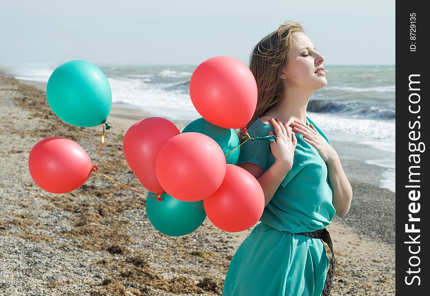 Emotional girl with balloons on the sea shore