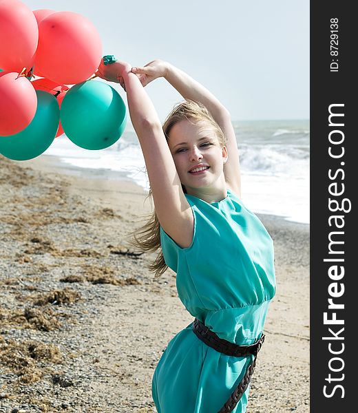 Emotional girl with balloons on the sea shore