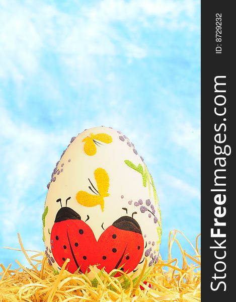 Easter egg in yellow straw on blue background
