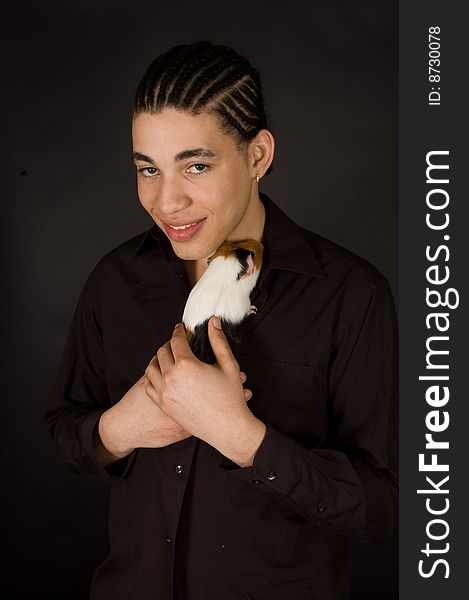 Aruban sexy male is holding a guinea pig on black