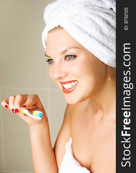 Beautiful happy young woman brushing teeth and smiling