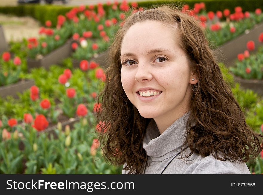 A pretty young girl poses in front of early spring flowers. A pretty young girl poses in front of early spring flowers