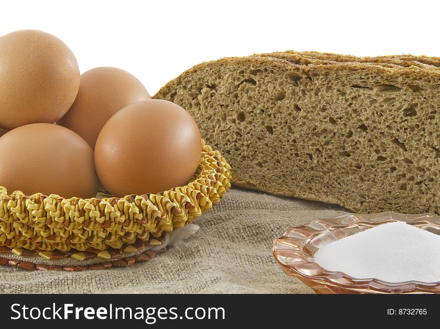 Still-life. Vegetarian products: rye bread from a flour of a rough grinding and the eggs lying in a wattled basket from straw on a sacking (a rough fabric)