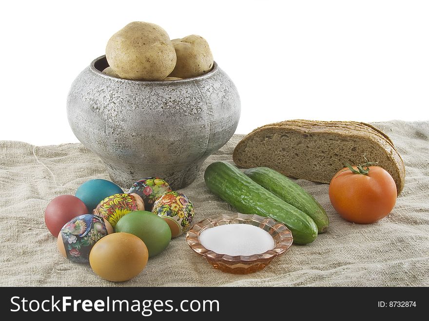 Still-life from vegetarian food. Fresh eggs lying in a wattled small basket, fragrant rye bread, a boiled potato in a pig-iron kettle, a saltcellar on a rough fabric