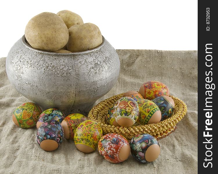 Still-life from vegetarian food. Fresh eggs lying in a wattled small basket,  boiled potato in a pig-iron kettle