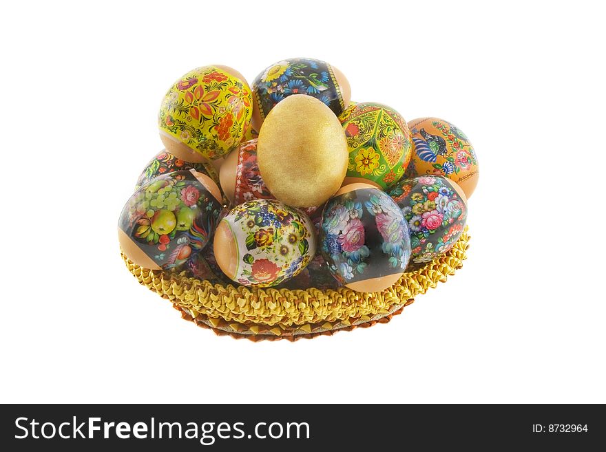 Many easter decorated eggs lying in a basket weaved from straw isolated over white background