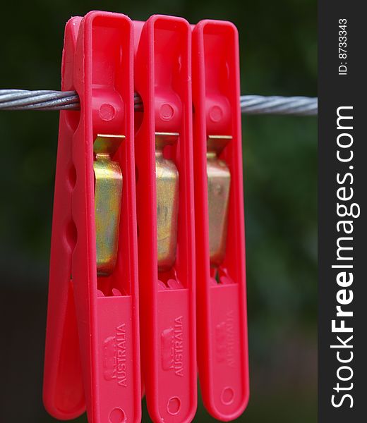 Three red pegs hanging on a clothes line. Three red pegs hanging on a clothes line