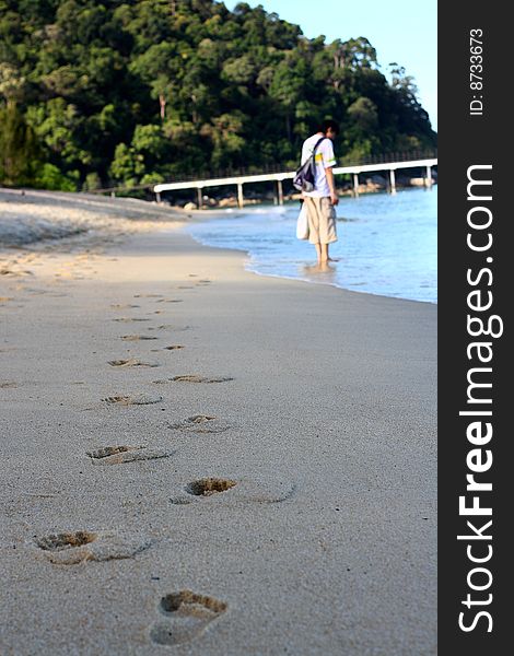 Man standing with footprints on beach