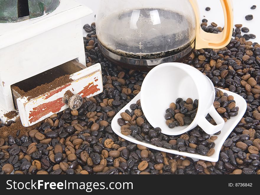 Cup of coffee over coffee grain with coffee pot
