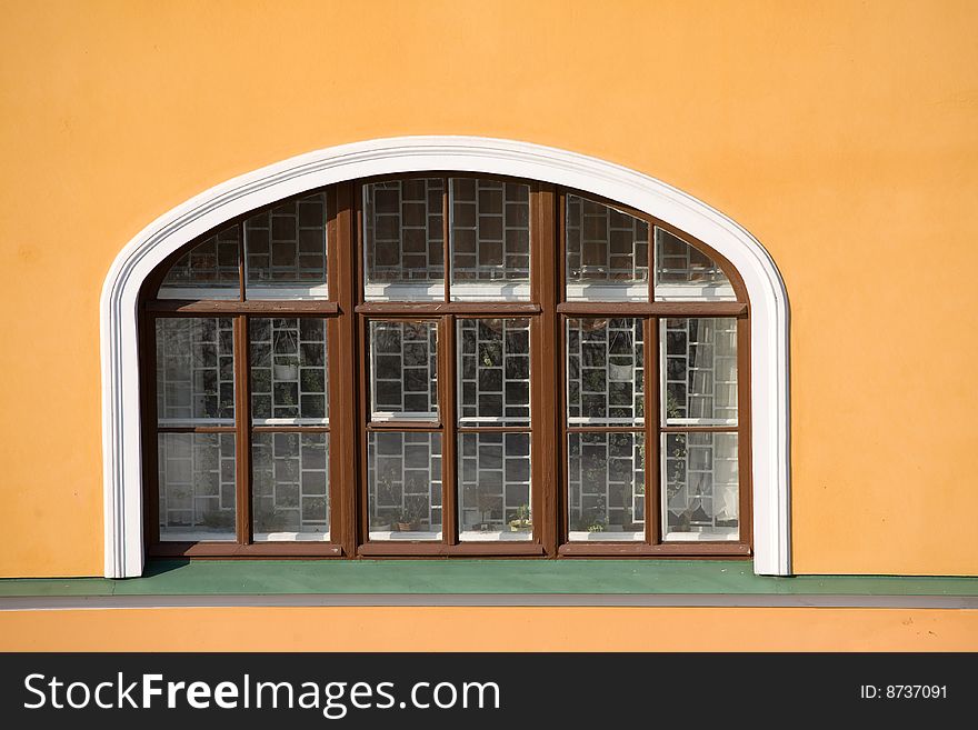 Window with grid in old yellow wall