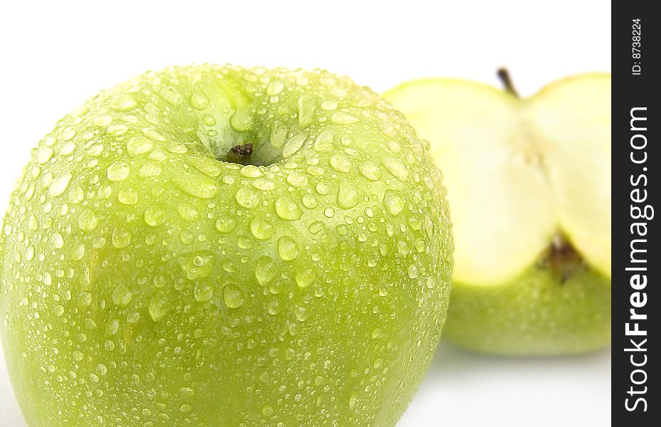 The whole green apple and half with drops of water on a white background. The whole green apple and half with drops of water on a white background