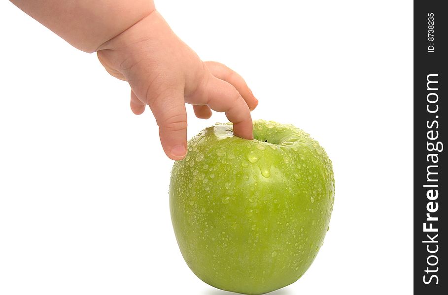 Hand of the child concerning a green apple with drops of water on a white background. Hand of the child concerning a green apple with drops of water on a white background
