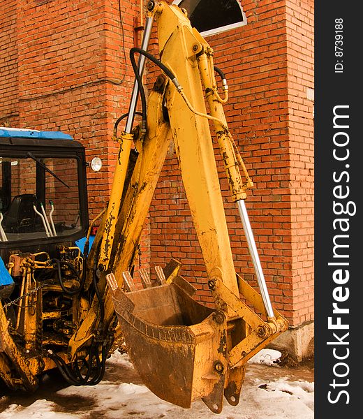 Part of the building mechanism with a ladle against a brick wall. Part of the building mechanism with a ladle against a brick wall