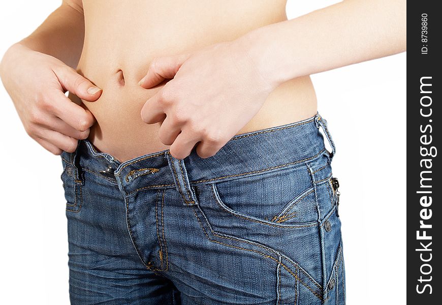 The girl measures the waist  in jeans on a white background. The girl measures the waist  in jeans on a white background